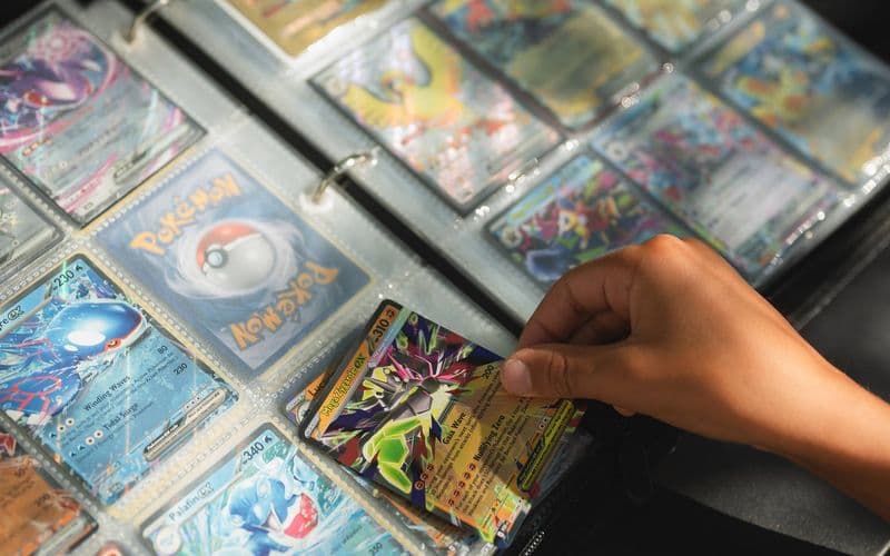 Một bàn tay lấy thẻ bài Pokémon ra khỏi album sưu tầm