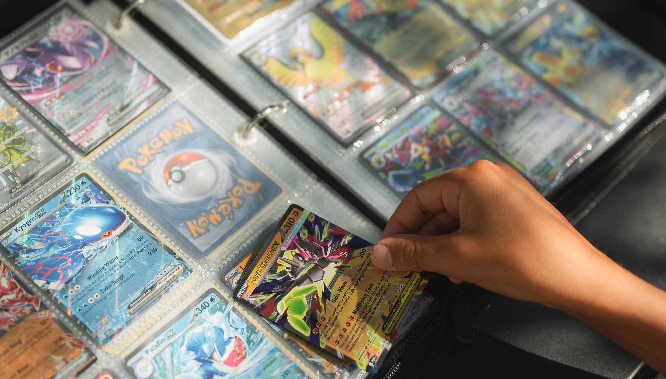 Một bàn tay lấy thẻ bài Pokémon ra khỏi album sưu tầm