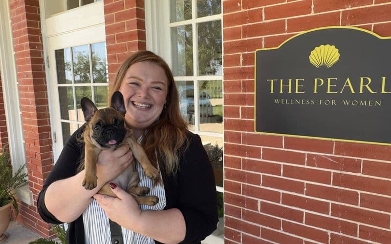Morgan Gaither bế chú chó bulldog Pháp Bougie trước cơ sở The Pearl Wellness for Women