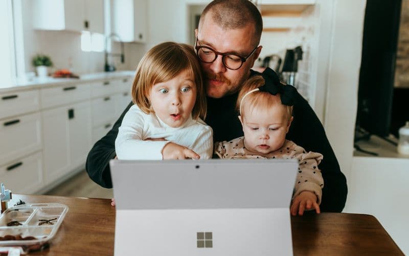 a man and two children looking at a laptop — Photo by Surface on Unsplash