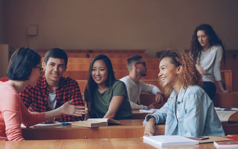 Students talking and laughing in a lecture hall — Photo by Vitaly Gariev on Unsplash